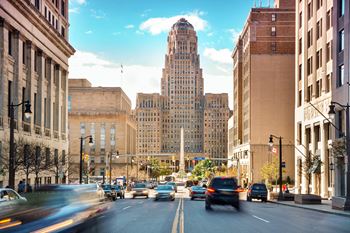 a busy city street with cars and a tall building